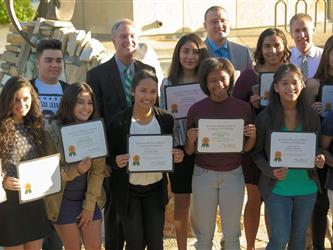 A group of students outside holding up certificates