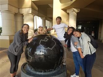 Students standing next to a spherical monument