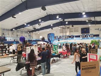 Students at a college fair; there are lots of cardboard stands